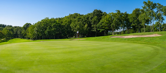 Fototapeta na wymiar Panorama View of Golf Course with beautiful putting green. Golf course with a rich green turf beautiful scenery.