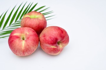 Studio shot of three apples on white background with areca palm leaf decoration.