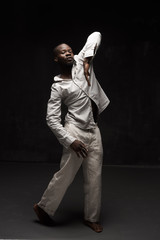 full-height photo of black man in linen suit on black background he waving his hands and looks in the camera - 297317490