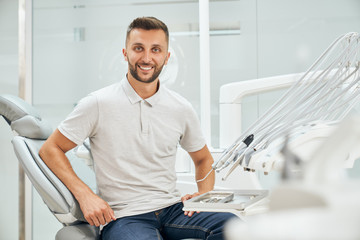 Fototapeta premium Front view of handsome male patient sitting on dental chair