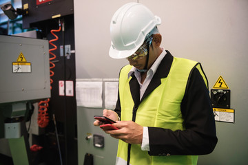 Factory engineer using smartphone at machine