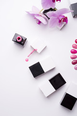 set for manicure with gel polish bottles, color palette and orchid on white background. close up. flat lay