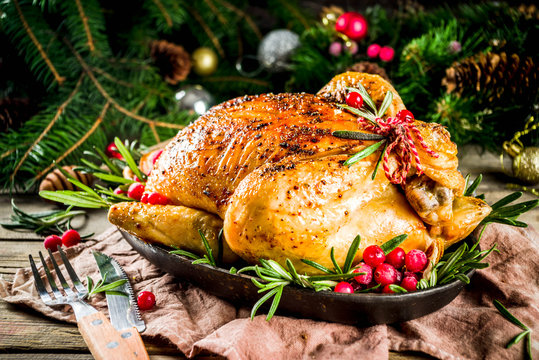 Traditional Christmas and Thanksgiving roasted whole chicken with fruit and rosemary. Rustic wooden background copy space with Christmas decoration