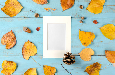 Autumn  composition  background.  Rusty yellow leaves ,  pinecone   and  acorn on blue background...