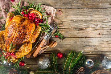 Traditional Christmas and Thanksgiving roasted whole chicken with fruit and rosemary. Rustic wooden background copy space with Christmas decoration