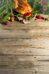 Traditional Christmas and Thanksgiving roasted whole chicken with fruit and rosemary. Rustic wooden table copy space with Christmas decoration