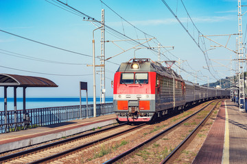 Passenger train moves along the platform by Black sea coast. Sochi.