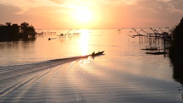View Silhouette Wooden boat fishermen net fishing in the lake at sunrise time.Amazing at Pak Pra Village Phatthalung, Thailand.4K footage