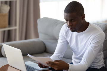 Serious biracial male read paperwork working from home