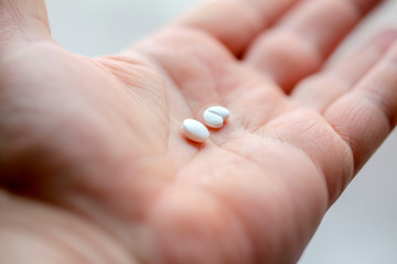 Two white pills in palm of white man. Medical product. Take medication.