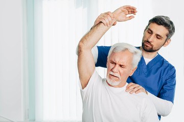 Senior patient while exercise treatment with his physiotherapist. Rehab at medical center