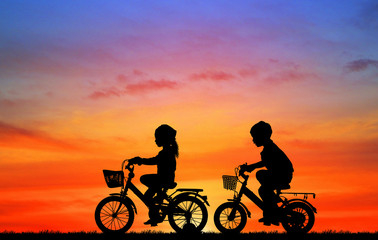 silhouette happy children  ride bike on sunrise