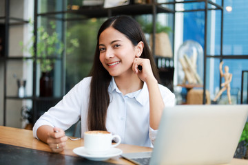 Asian woman working and drink coffee in cafe with laptop computer smile and happy work