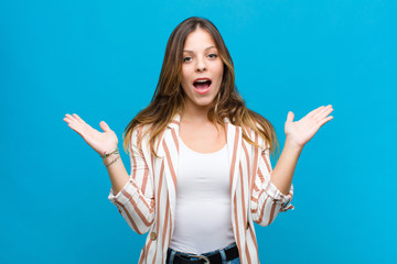 young pretty woman feeling happy, excited, surprised or shocked, smiling and astonished at...
