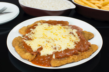 Parmigiana steak with french fries and rice in black background