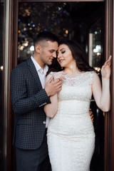 Fototapeta premium Handsome guy in suit and girl in white dress. Fashionable photo of young people. Romantic youth concept. Young stylish couple pose. Love and tenderness. Happy lovers and family. 