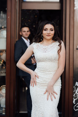 Trendy couple coming out of modern cafe.  Love story. Lifestyle concept.  Feelings of love between two people. Fashion photo. Guy in suit and Beautiful woman with professional make up and hairstyle.