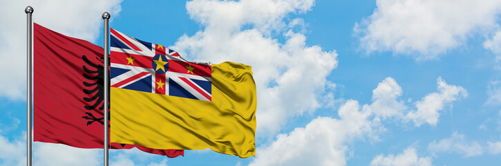 Albania and Niue flag waving in the wind against white cloudy blue sky together. Diplomacy concept, international relations.