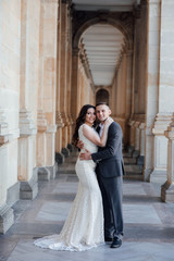 Fashion photo. Young elegant sexy couple hugs, wearing suit and  white dress with a train, enjoy their honeymoon, luxury style, love, stylish lovers. Love story. Lifestyle concept.