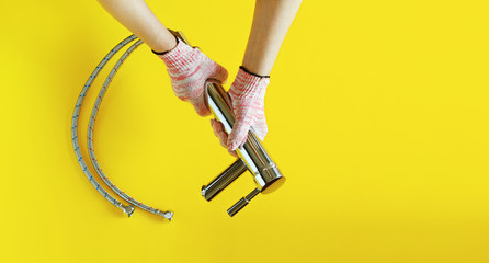 Woman holding in hands to repair faucet with cotton work gloves on. Isolated on yellow background. 