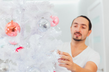 Fototapeta premium man dresses up Christmas tree. Christmas time