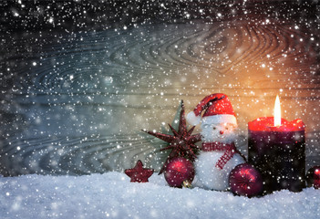 Christmas snowy background with fourth Advent candle and Snowman .