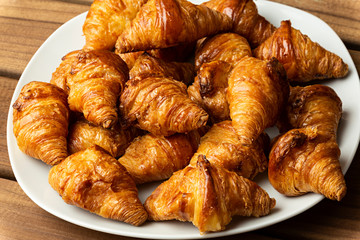 Croissant en plato sobre fondo de madera.
