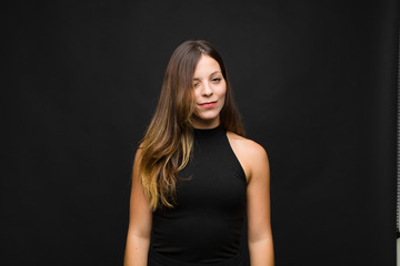 young pretty woman looking happy and friendly, smiling and winking an eye at you with a positive...
