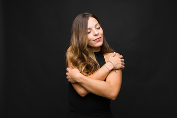 young pretty woman feeling in love, smiling, cuddling and hugging self, staying single, being...