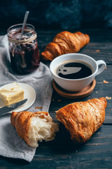 delicious croissants with coffee on dark wooden table