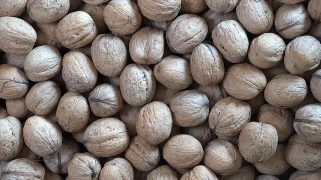 Walnuts in shell close up, top view. Abstract walnuts heap pattern background, rotates. Natural walnut background pattern texture