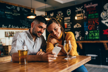 friends using smartphone while waiting for food in food corner bar