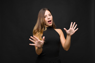 young pretty woman feeling terrified, backing off and screaming in horror and panic, reacting to a...
