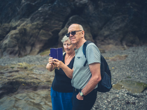Senior couple taking photos with smartphone on the beach