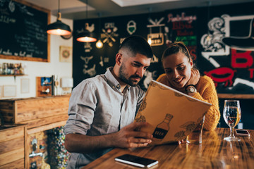 couple ordering food looking at menu in food corner bar
