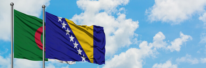 Algeria and Bosnia Herzegovina flag waving in the wind against white cloudy blue sky together....