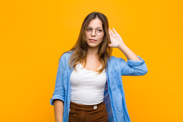 young pretty woman looking serious and curious, listening, trying to hear a secret conversation or...