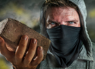 young man as ultra and radical anarchist rioter . furious antifa protester in face mask throwing...