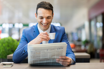 Young manager having a coffee and reading a newspaper