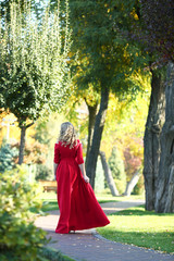 Obraz na płótnie Canvas beautiful woman in a red dress walks in the autumn park