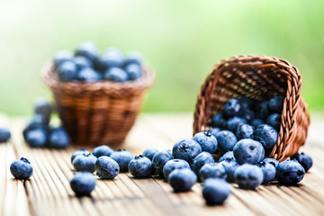 Blueberries on wooden rustic table. Wicker basket full of blueberry in background.