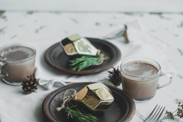 Christmas and New Year table setting in rustic style with handmade details. Dining place decorated with handmade dishes, pine cones, branches and golden christmas decorations 