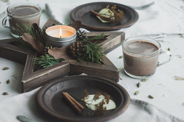 Obraz na płótnie Canvas Star-shaped Wooden Tray with two cups of cocoa. Christmas decor with rustic style elements on a white background. Cones and pine branches New Year's decor.