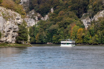Passenger ship passing Danube breakthrough near Kelheim, Bavaria, Germany in autumn with gravel...