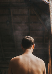 A naked man is standing in the sauna. Rear view
