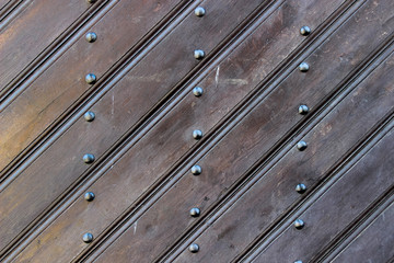 Texture of an old worn varnished panels riveted with button-head rivets as a background