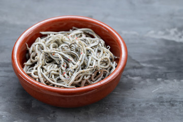 Traditional Spanish food. Gulas with oil in ceramic dish.