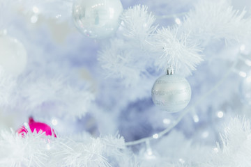 Obraz na płótnie Canvas Close up of a Christmas ball in a white fir tree with lights background