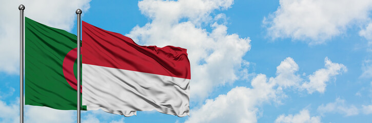 Fototapeta na wymiar Algeria and Indonesia flag waving in the wind against white cloudy blue sky together. Diplomacy concept, international relations.