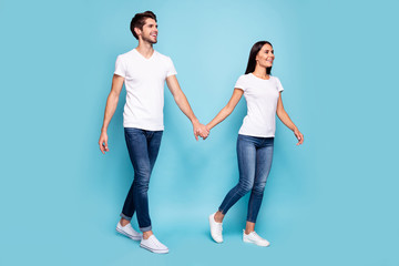 Fototapeta na wymiar Full length body size view of his he her she nice attractive cheerful cheery spouses holding hands walking spending weekend isolated over bright vivid shine vibrant blue green turquoise background